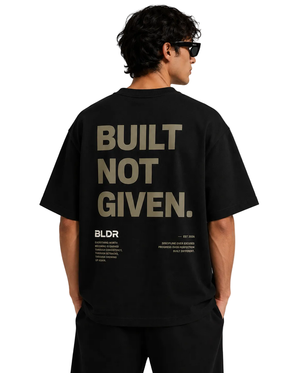 Person wearing a black t-shirt with 'BUILT NOT GIVEN' text on the back, standing against a plain background.