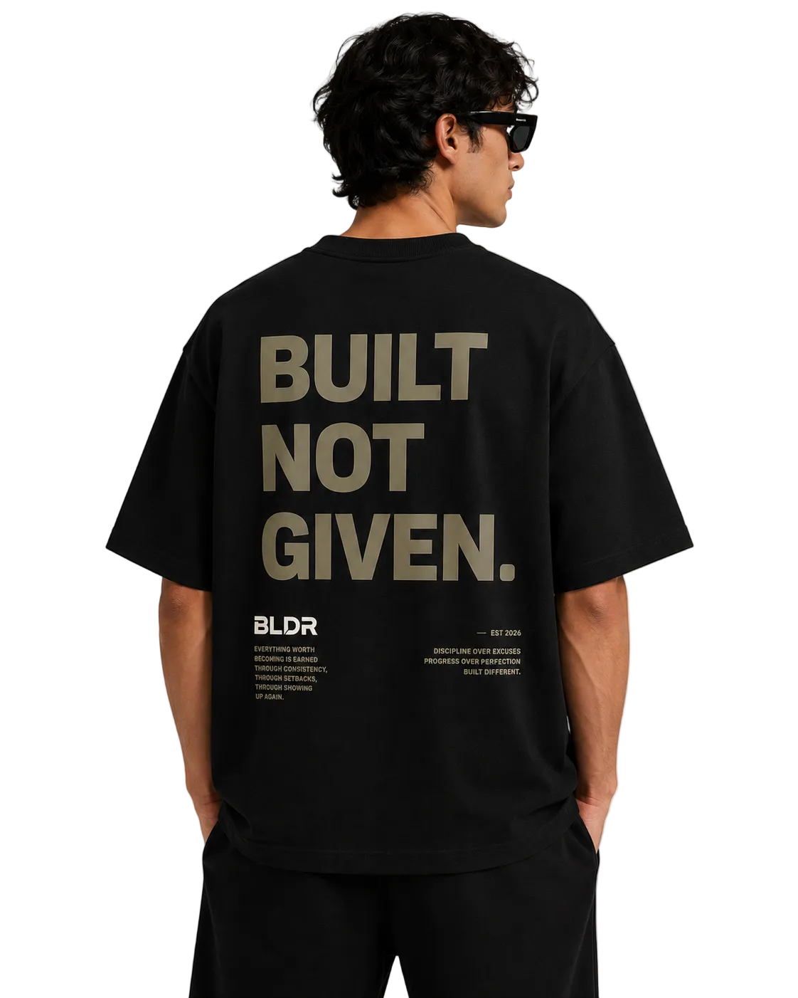 Person wearing a black t-shirt with 'BUILT NOT GIVEN' text on the back, standing against a plain background.