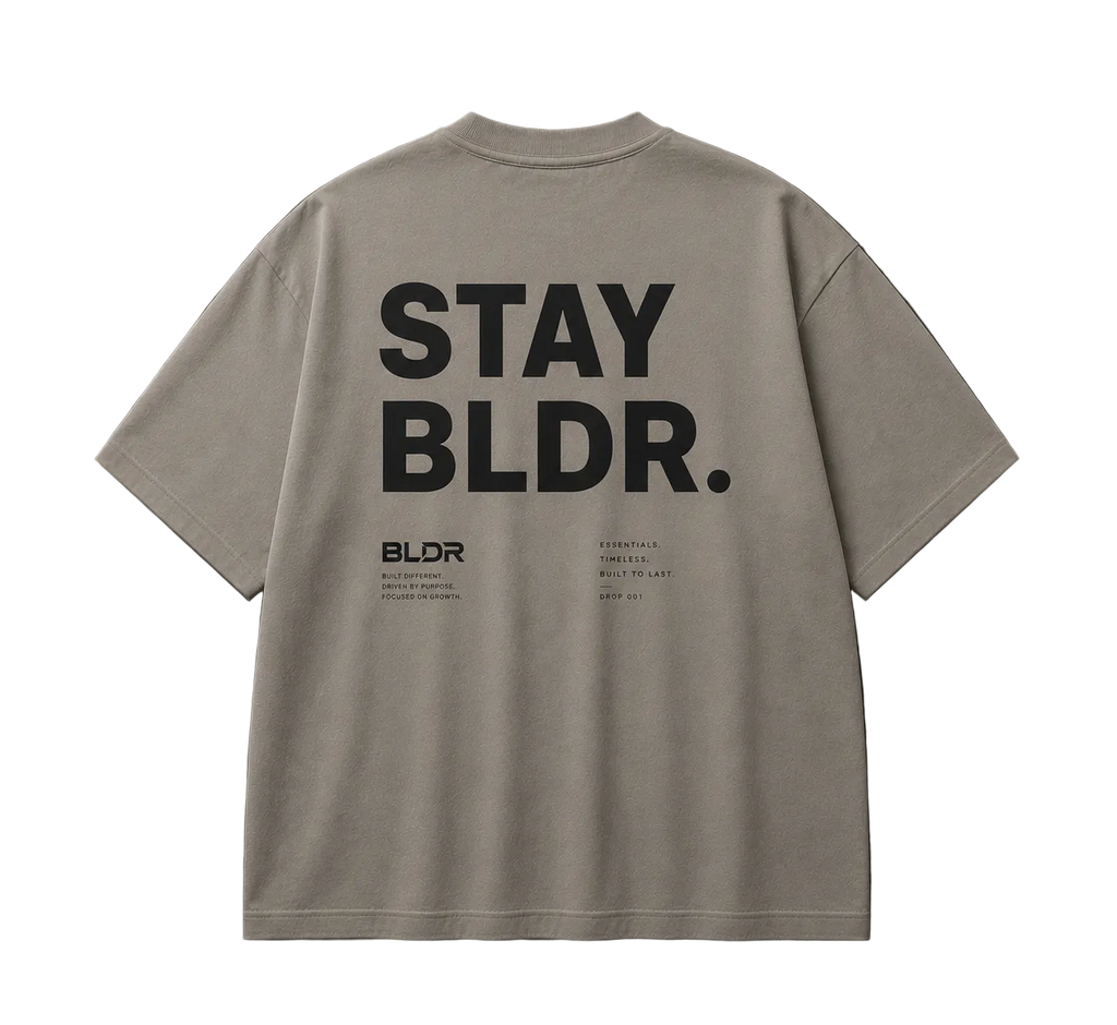 Beige t-shirt with 'STAY BLDR.' text on the back against a gray background