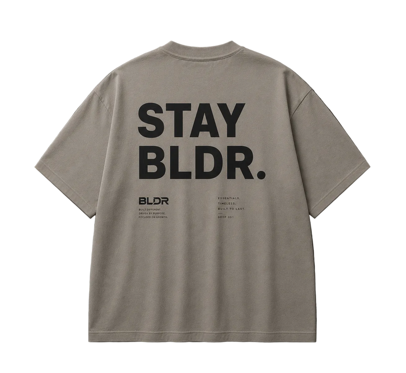 Beige t-shirt with 'STAY BLDR.' text on the back against a gray background