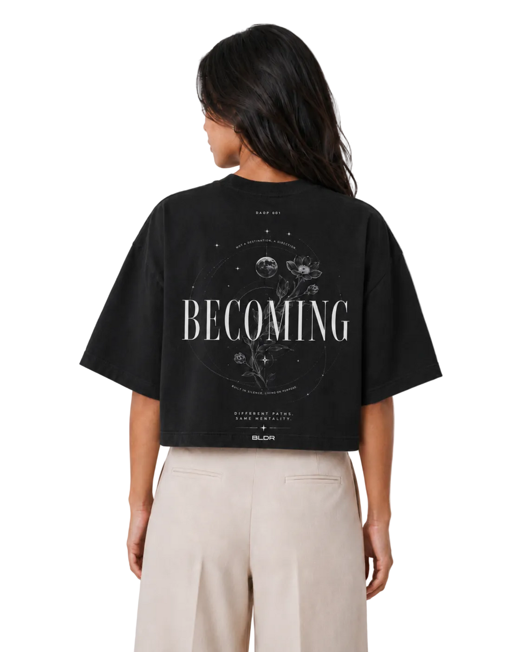 Person wearing a black t-shirt with 'BECOMING' printed on the back against a plain background