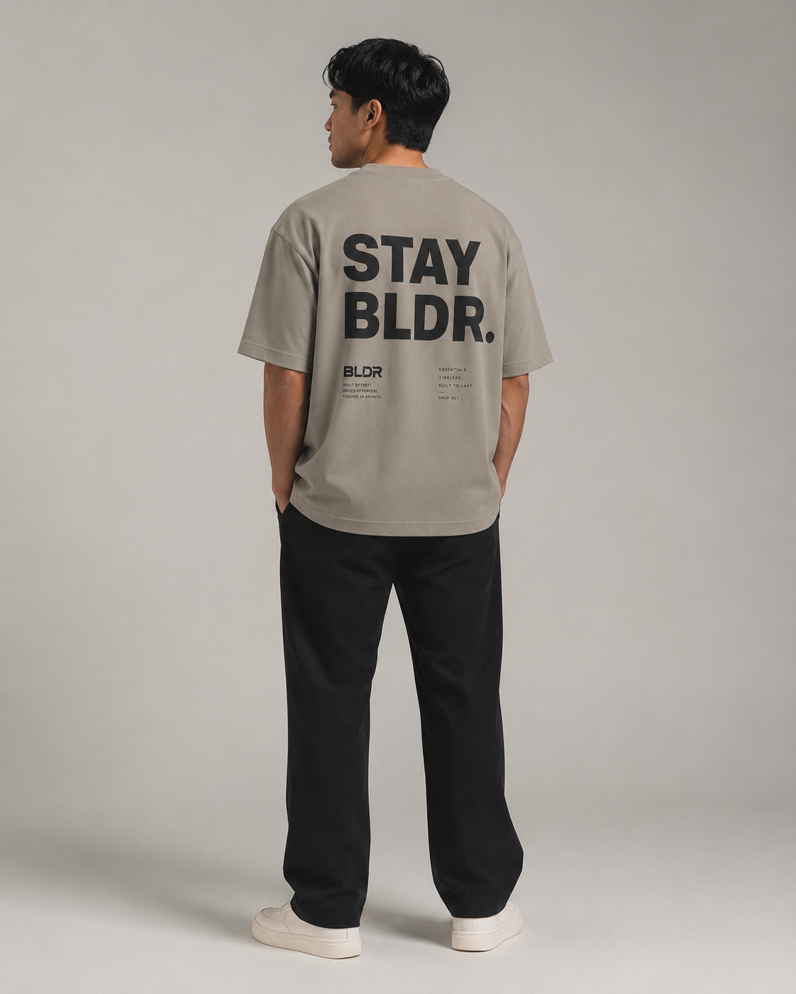 Person wearing a beige t-shirt with 'STAY BLDR.' text on the back, standing against a plain background.
