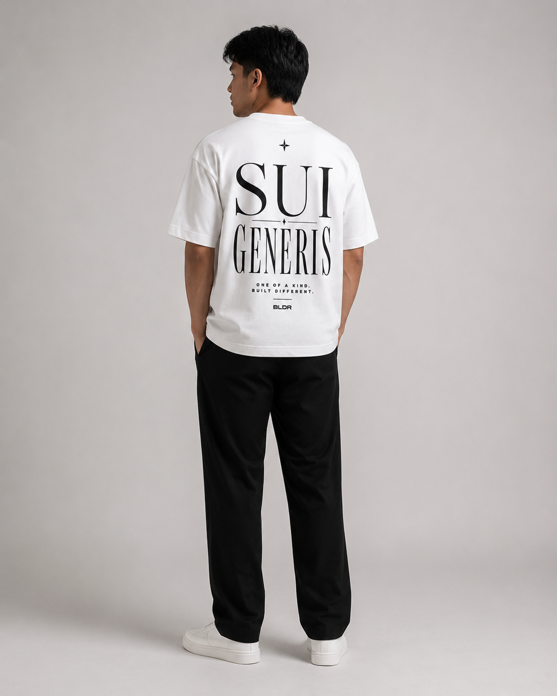 Person wearing a white t-shirt with 'SUI GENERIS' text and black pants on a gray background